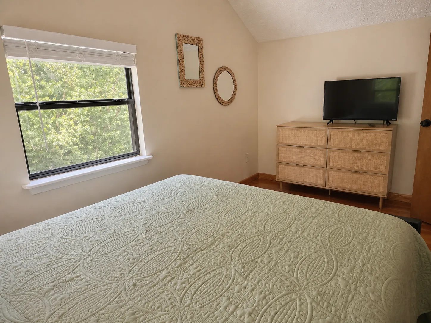 Queen bedroom with a rattan dresser and a TV