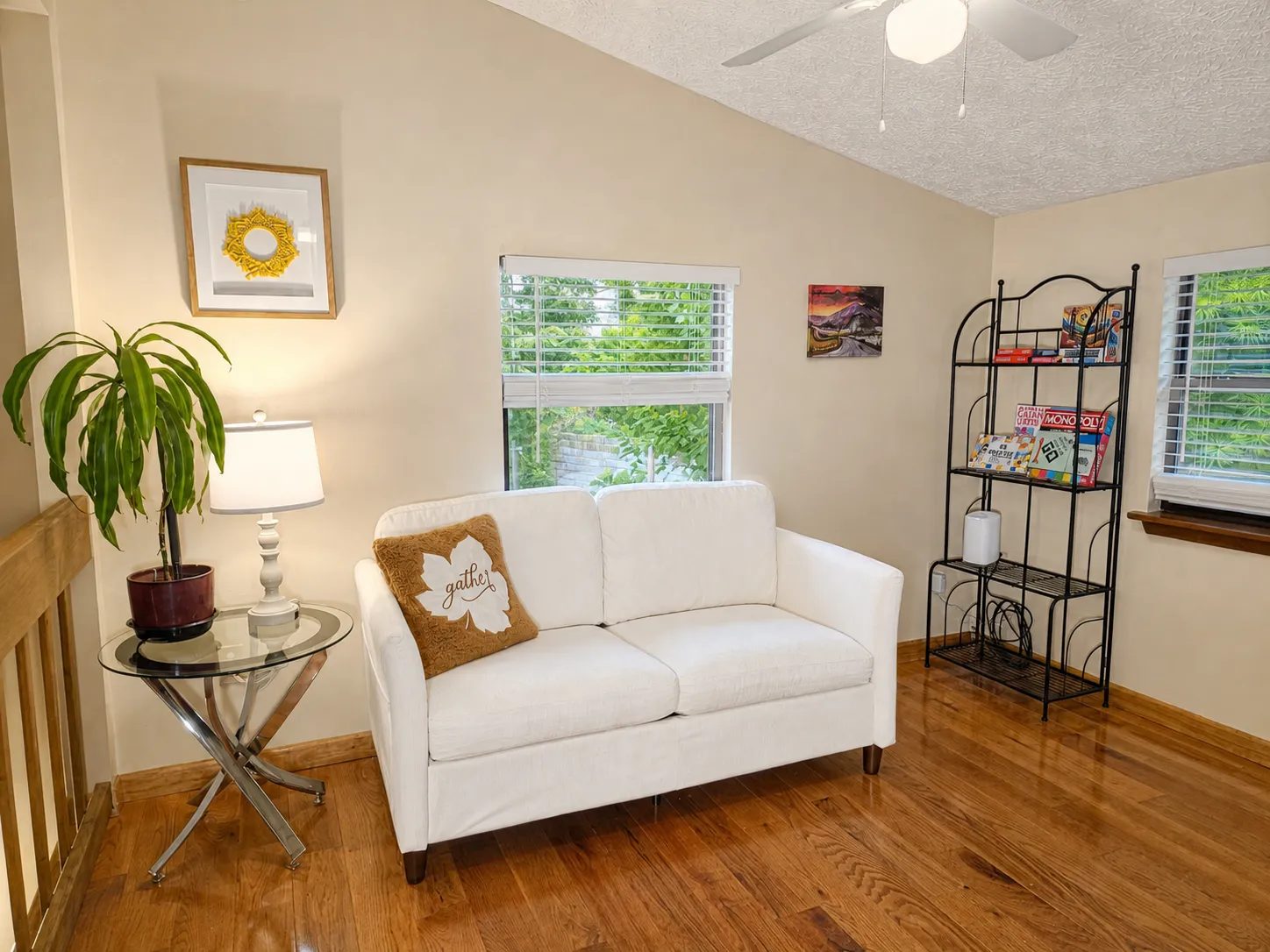 Loft sitting area with a white loveseat and a shelf of board games