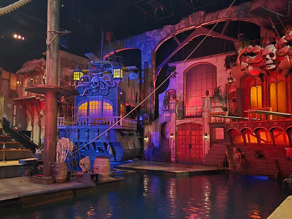 Pirate ships lit in red and blue on the indoor lagoon of a dinner show theater